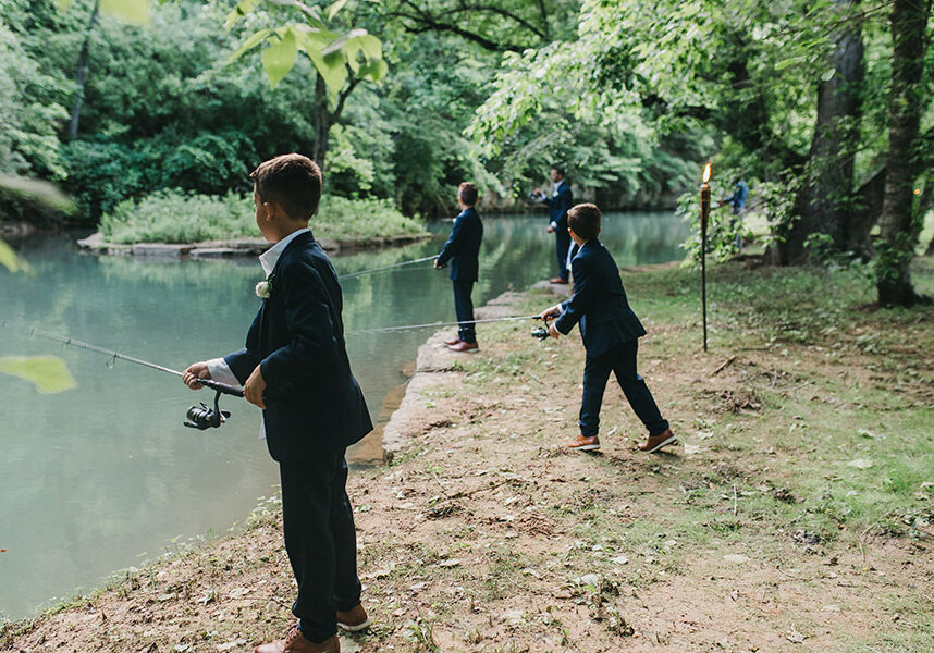 2025_DWC_Wedding_KidsFishing_1 Young boys fishing at Dogwood Canyon after wedding ceremony in their suits.